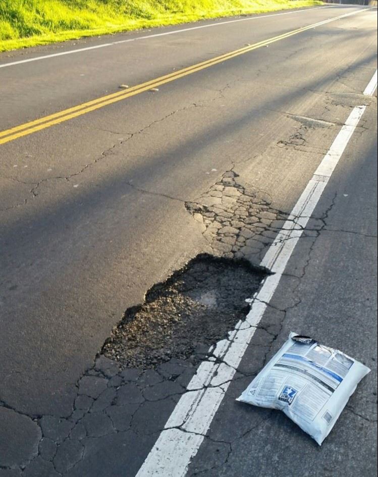 pothole - hole in street with bag of asphalt repair material 